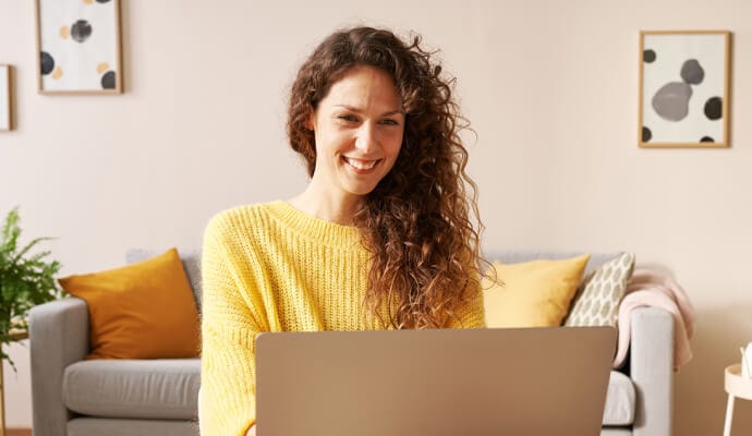 女子笑着用笔记本电脑启动 Norton Safe Search。